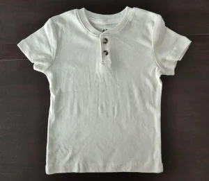Shirt Parts Name: Easy Overview with Size Chart Guide a white henley t-shirt on the table